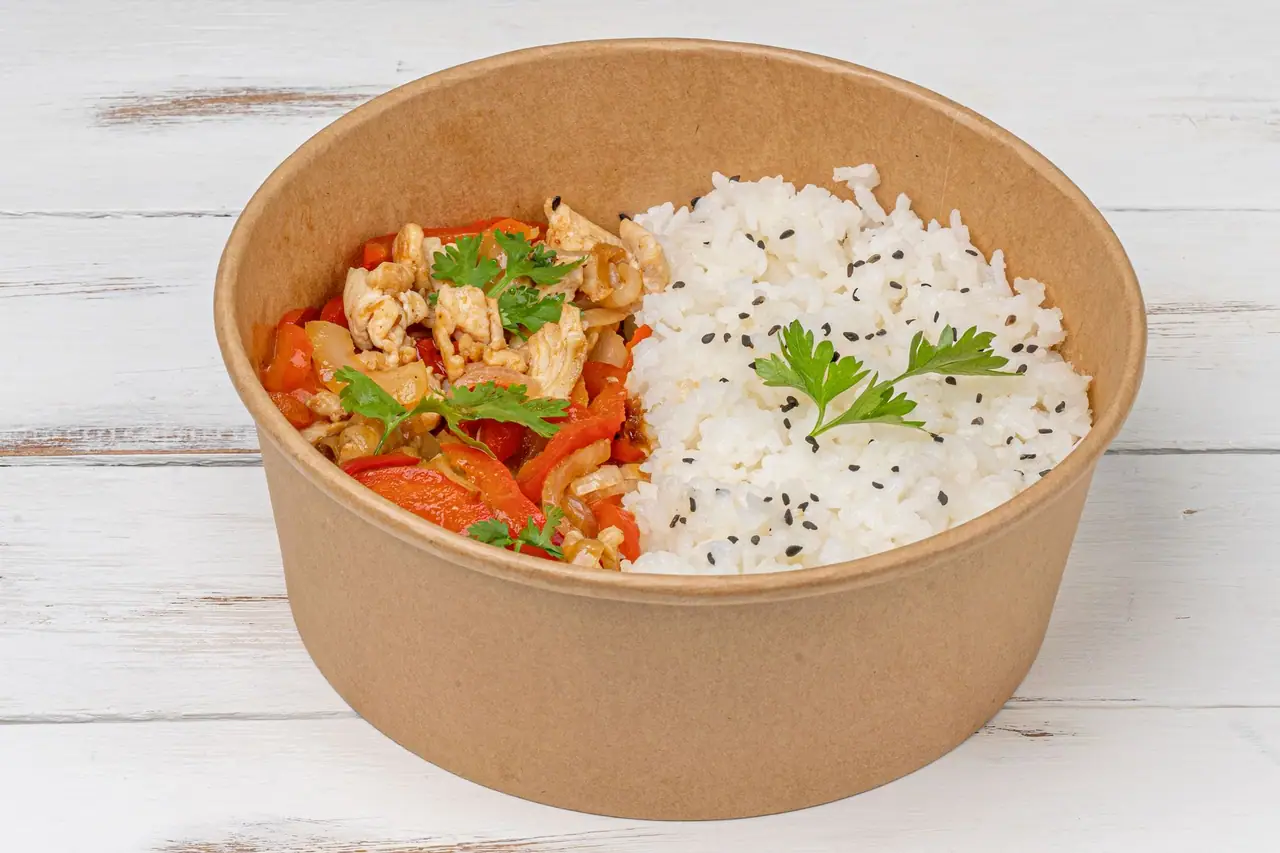 Rice and stir-fried vegetables in a kraft paper bowl