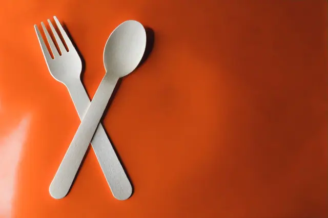 Wooden fork and spoon on an orange background