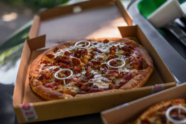 Pizza in an open kraft corrugated pizza box